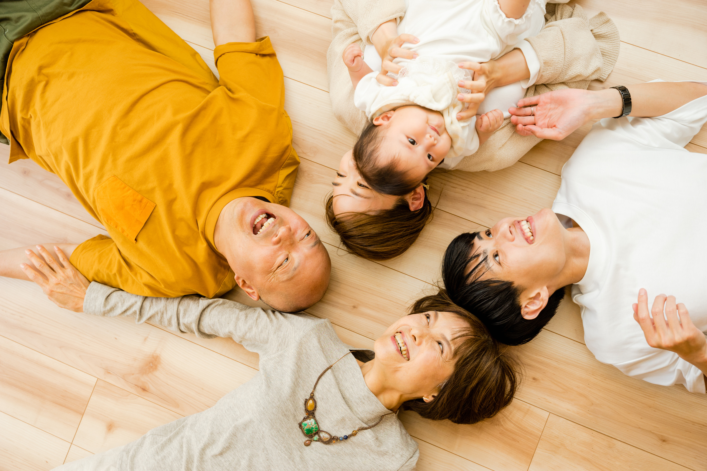 Five families of 3rd generation of babies, parents and grandparents who lie upwards on the floor